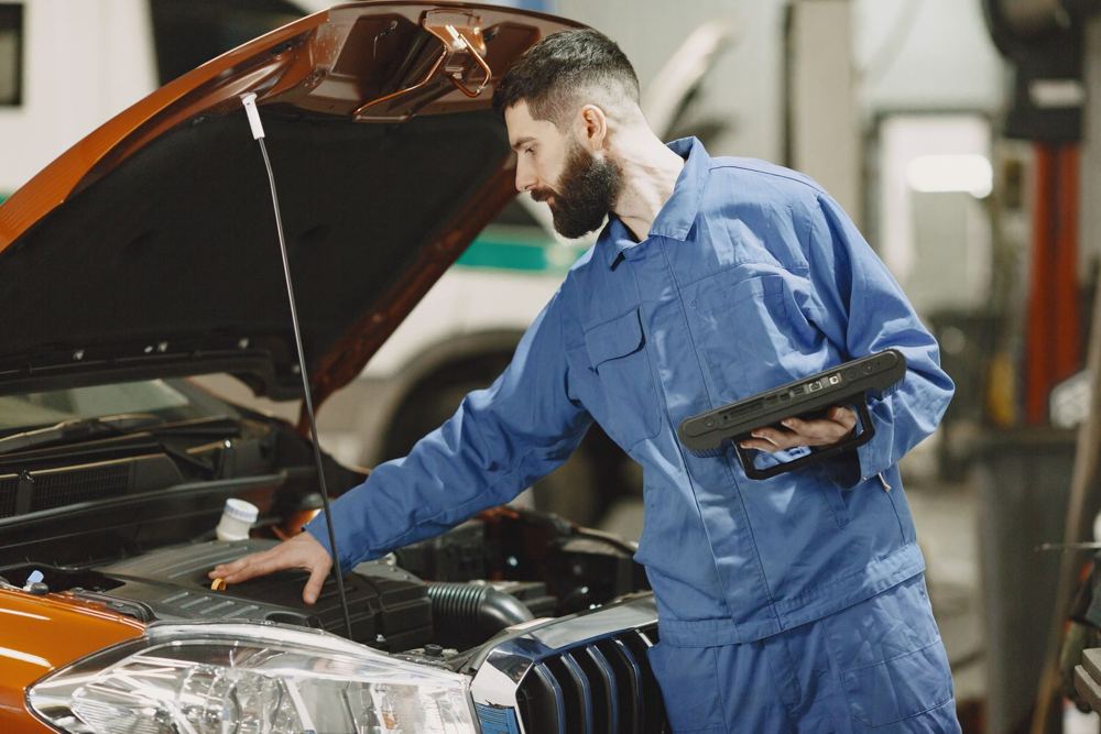 Mechanic checking a car engine with a tablet