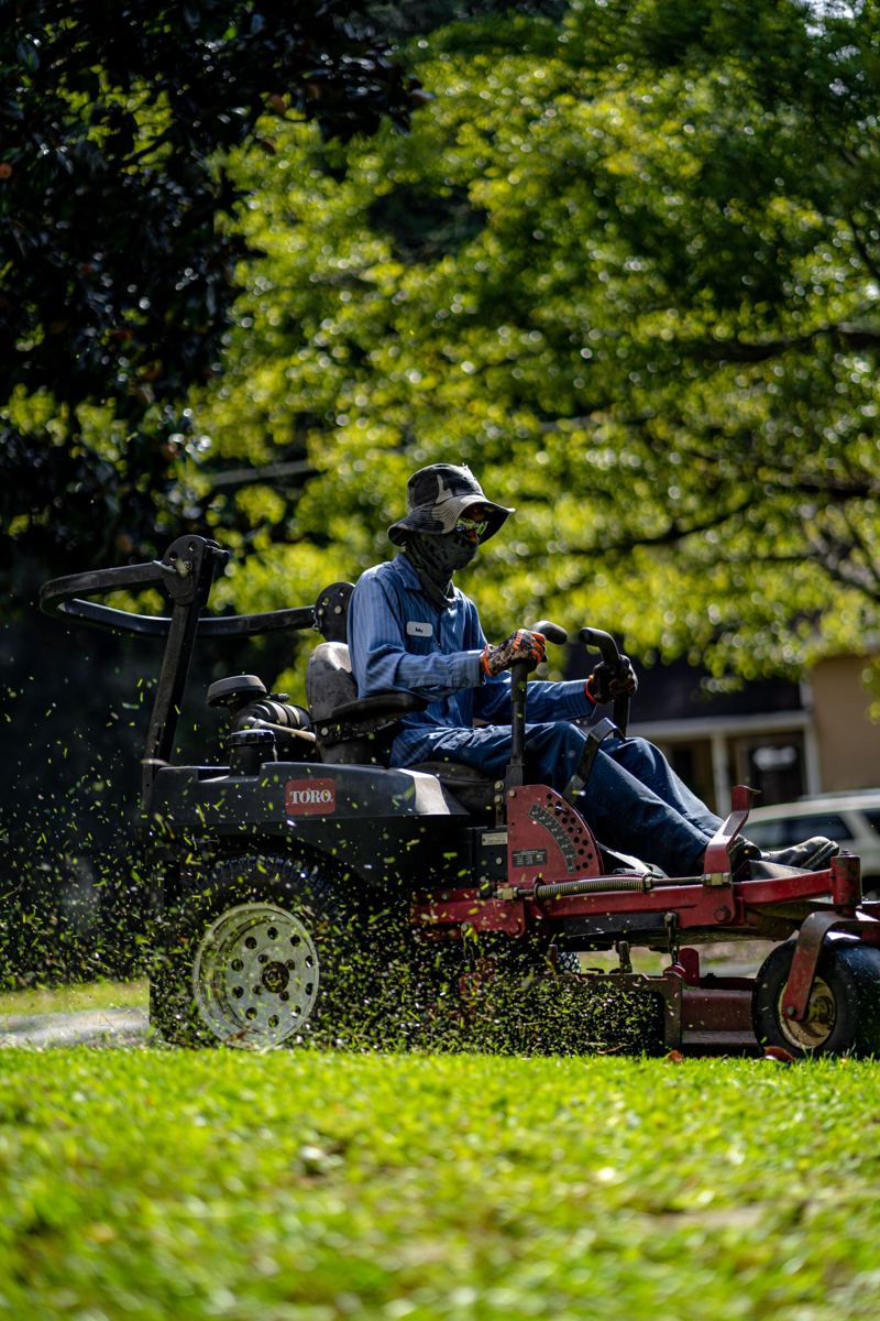 Landscaper mowing a lawn on a ride-on mower